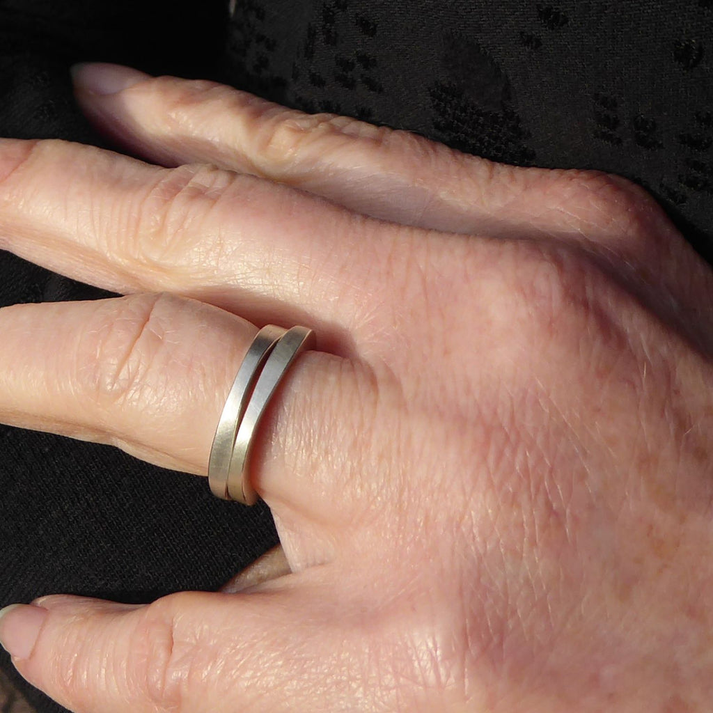 zwei-zusammen-am-finger-getragene-ringe-mit-dem-namen-durch-dick-und-duenn-die-ringe-bestehen-aus-sterling-silber-die-form-ist-klassisch-aber-leicht-unregelmaessig-an-manchen-stellen-dicker-an-manchen-stellen-duenner-durch-die-kombination-der-beiden-ringe-die-ringe-entsteht-eine-spannende-wechslewirkung-die-ringe-werden-von-hand-in-unserer-goldschmiede-in-frankfurt-am-main-angefertigt-das-modell-eignet-sich-auch-gut-als-ehering