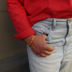 zu-einer-roten-Bluse-und-jeans-getragener-schlichter-handgefertigter-ast-armreif-mit-feiner-struktur-von-echten-aestchen-abgeformt-in-vergoldetem-sterling-silber-aus-unserer-goldschmiede-in-frankfurt-auch-in-fairtrade-gold-oder-fairmined-silber-erhaeltlich-die-groesse-ist-leicht-anpassbar-alexandra-baum-schmuck