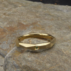 ein-ganz-schmaler-ring-mit-vielen-unregelmaessigen-facetten-beziehungsweise-polygonen-flaechen-der-ring-ist-ca-zweieinhalb-millimeter-breit-und-besteht-aus-gelbgold-er-ist-auch-in-fairtrade-gold-erhaeltlich-auf-einer-facette-ist-vollflaechig-ein-gruener-brillant-der-ring-wurde-fuer-unsere-kundin-aus-dem-ring-ihres-verstorbenen-mannes-gemacht-die-ringe-werden-von-hand-in-unserer-goldschmiede-in-frankfurt-am-main-angefertigt-alexandra-baum-schmuck
