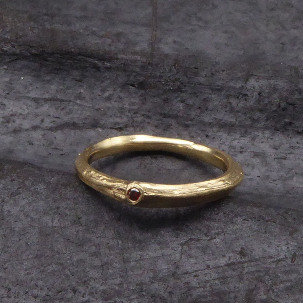 ein-ring-in-gelbgold-aus-einem-kleinen-ast-geformt-in-einem-blattansatz-funkelt-ein-roter-brillant