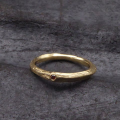 ein-ring-in-gelbgold-aus-einem-kleinen-ast-geformt-in-einem-blattansatz-funkelt-ein-roter-brillant