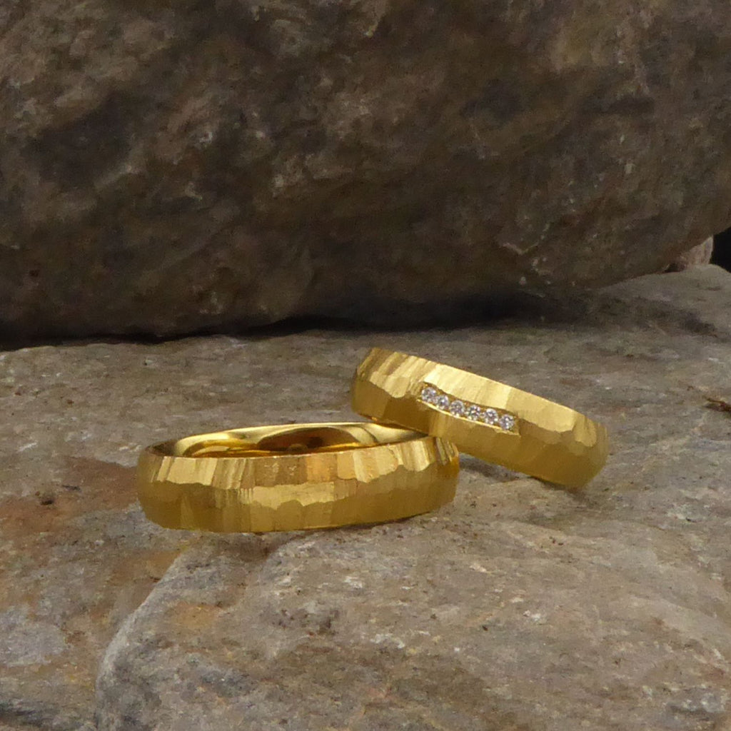 ein-paar-trauringe-mit-geriffelter-struktur-die-in-drei-linien-abwechslungsreich-um-den-ring-laeuft-die-ringe-bestehen-aus-gelbgold-und-der-damenring-ist-mittig-mit-sechs-brillanten-besetzt-handgefertigt-von-alexandra-baum-schmuck-in-frankfurt