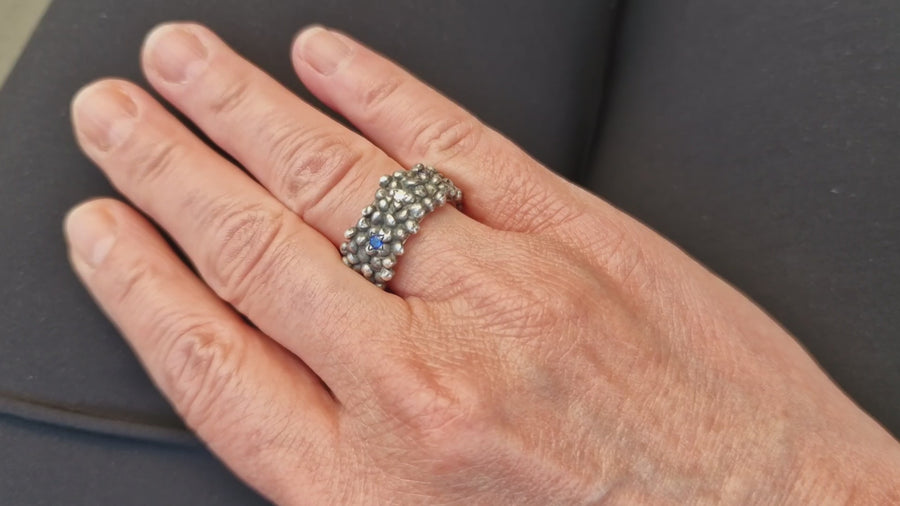 breiter-bubble-ring-mit-ca-zwei-millimeter-grossen-kuegelchen-mit-eingefassten-brillanten-und-saphiren-der-ring-besteht-aus-sterling-silber-und-ist-aussen-geschwaerzt-er-wird-in-unserer-werkstatt-in-fankfurt-am-main-von-hand-angefertigt-der-ring-hat-einen-leichten-used-look-und-die-steine-funkeln-schoen