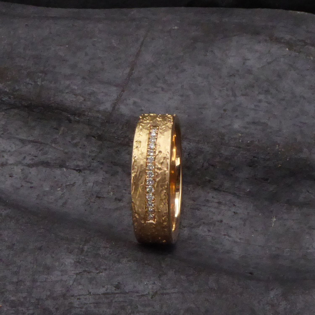 ein-breiter-trauring-mit-rinden-struktur-in-rosegold-mit-einer-linie-aus-vierzehn-diamanten-besetzt-von-alexandra-baum-schmuck-frankfurt