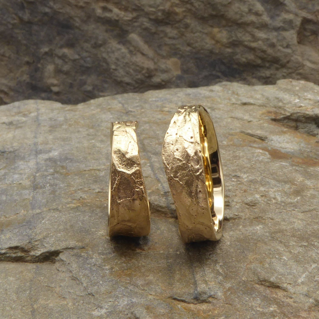ein-paar-trauringe-in-fairtrade-gelbgold-mit-ergonomischer-form-und-einer-walnuss-struktur-auf-der-oberflaeche