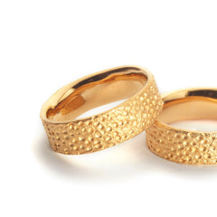 zwei-gelbgoldene-ringe-mit-einer-oberflaechen-struktur-die-an-eine-mond-landschaft-mit-kratern-erinnert-von-alexandra-baum-schmuck-in-frankfrt