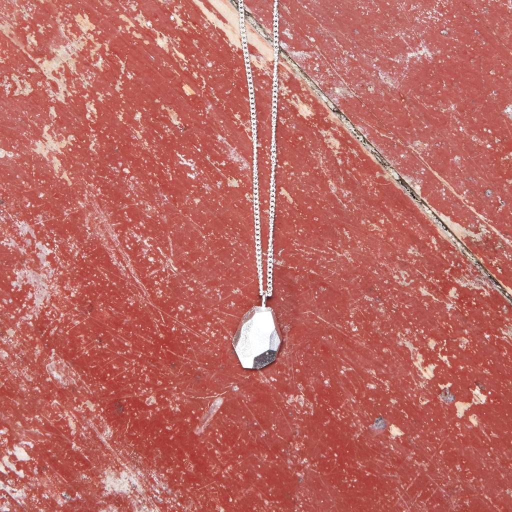 ecken-und-kanten-kette-mit-einem-kleinen-tropfenfoermigen-anhaenger-mit-unregelmaessigen-facetten-die-kette-besteht-aus-recycling-sterling-silber-als-verschluss-der-kette-ist-ein-karabiner-befestigt-den-man-auf-zwei-verschiedene-laengen-einhaken-kann-nachhaltiger-schmuck-von-hand-gefertigt-in-unserer-goldschmiede-in-frankfurt-bockenheim
