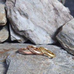 drei-ganz-schmale-ringe-mit-vielen-unregelmaessigen-facetten-beziehungsweise-polygonen-flaechen-die-ringe-sind-ca-zweieinhalb-millimeter-breit-und-bestehen-aus-gelbgold-rosegold-oder-rotgold-sie-sind-auch-in-fairtrade-gold-erhaeltlich-design-trauringe-oder-verlobungsringe-die-nicht-von-der-stange-sind-die-ringe-werden-von-hand-in-unserer-goldschmiede-in-frankfurt-am-main-angefertigt-alexandra-baum-schmuck