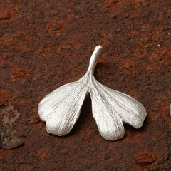mittelgroßer-handgefertigter-ginkgo-anhänger-mit-feiner-struktur-von-echten-ginkgoblaettern-abgeformt-ohne-kette-in-sterling-silber-aus-unserer-goldschmiede-in-frankfurt-auch-in-fairtrade-gold-erhaeltlich-geschwungene-form-mit-einem-schlitz-und-wellen-an-den-blattspitzen-ungefaehr-37-millimeter