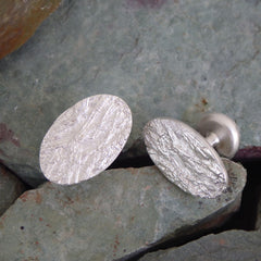 ein-paar-handgefertigte-manschetten-knoepfe-mit-gras-struktur-aus-sterling-silber-sie-bestehen-aus-einem-ovalen-und-einem-runden-plaettchen-die-mit-einem-festen-runden-steg-verbunden-sind-das-kleinere-runde-plaettchen-wird-wie-ein-knopf-durch-die-loecher-der-manschetten-gezogen-alexandra-baum-schmuck-frankfurt