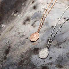 zwei-gras-anhaenger-ketten-jeweils-mit-einem-eirigen-anhaenger-mit-der-struktur-von-abgeformtem-gras-eine-kette-besteht-aus-rose-vergoldetem-recycling-sterling-silber-und-die-andere-aus-recycling-silber-als-verschluss-der-ketten-ist-jeweils-ein-karabiner-befestigt-den-man-auf-zwei-verschiedene-laengen-einhaken-kann-nachhaltiger-schmuck-von-hand-gefertigt-in-unserer-goldschmiede-in-frankfurt-bockenheim-alexandra-baum-schmuck